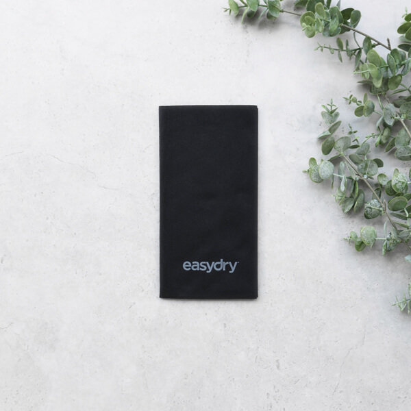 Easydry black medium towel. It is shown here folded with some leaves.