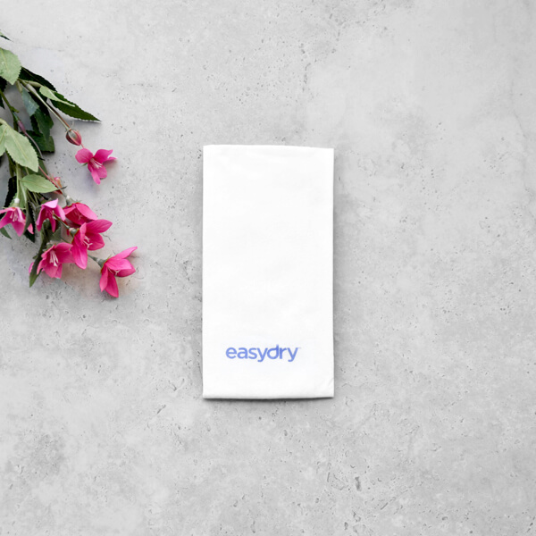 Easydry white medium towel. It is shown here folded with some leaves.